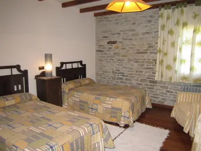 a bedroom with two beds and a brick wall at A Lareira in Chan de Vilar
