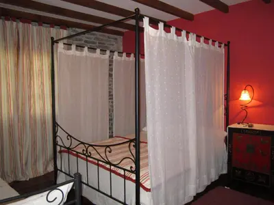a bedroom with a canopy bed with white curtains at A Lareira in Chan de Vilar