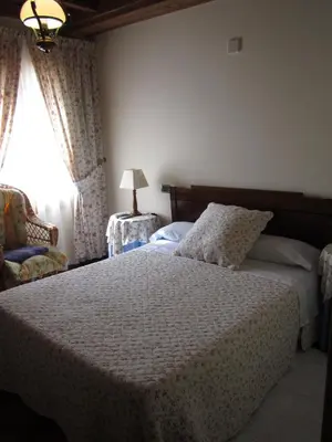 a bedroom with a bed and a lamp and a window at A Lareira in Chan de Vilar