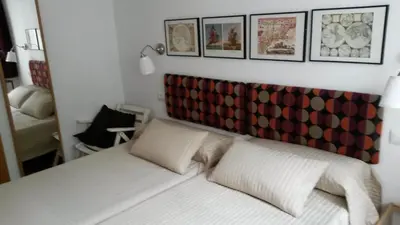 a bedroom with a white bed with a red headboard at Apartamentos el Camino in Villafranca del Bierzo