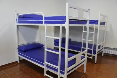 two bunk beds in a room with blue sheets at Albergue Folgueira in Portomarin