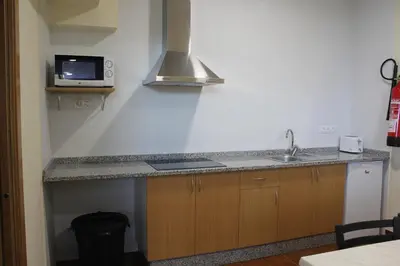 a kitchen with a sink and a microwave at Albergue Folgueira in Portomarin