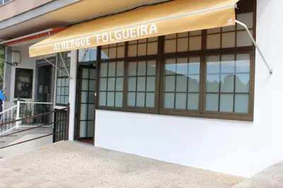a building with a sign that reads integrative polisheria at Albergue Folgueira in Portomarin