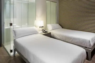 a bedroom with two beds and a glass wall at Hotel Atalaia in Santiago de Compostela