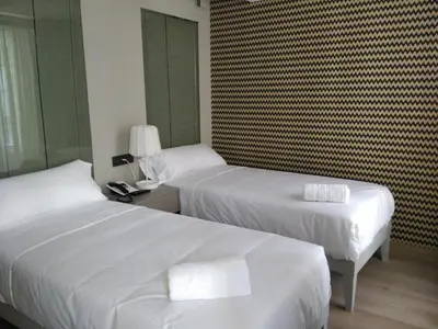 two beds in a hotel room with white sheets at Hotel Atalaia in Santiago de Compostela