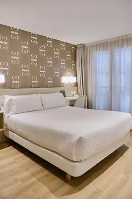a bedroom with a large white bed and a window at Hostal Suso in Santiago de Compostela