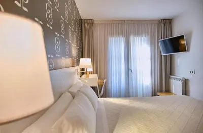 a hotel room with a bed and a flat screen tv at Hostal Suso in Santiago de Compostela