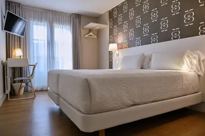 a bedroom with a large bed with a wall with clocks at Hostal Suso in Santiago de Compostela