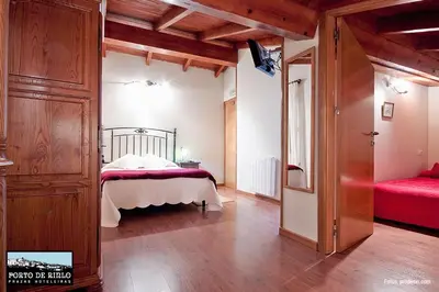 a bedroom with a bed and a red couch in it at Porto de Rinlo in Rinlo