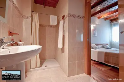a bathroom with a sink and a shower and a bed at Porto de Rinlo in Rinlo