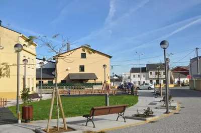 a park with a bench on a city street at Porto de Rinlo in Rinlo