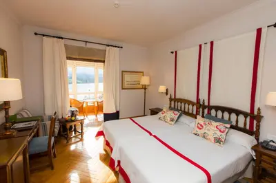 a bedroom with a bed and a desk and a window at Parador de Ribadeo in Ribadeo