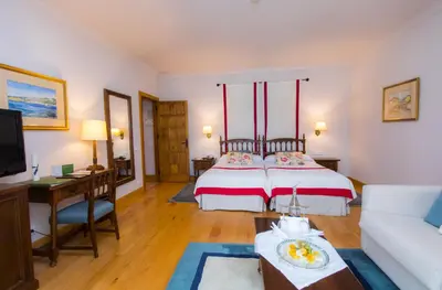 a bedroom with a bed and a desk and a couch at Parador de Ribadeo in Ribadeo