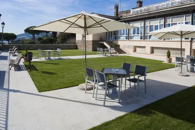 a patio with tables and chairs and an umbrella at Parador de Ribadeo in Ribadeo
