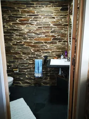 a bathroom with a stone wall and a sink at Pensión Santa Rosa in Samos