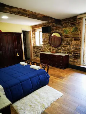 a bedroom with a blue bed and a stone wall at Pensión Santa Rosa in Samos