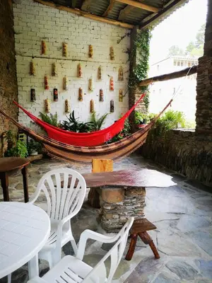 a hammock on a brick wall with chairs and a table at Pensión Santa Rosa in Samos