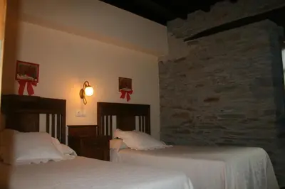 a bedroom with two beds and a stone wall at Apartamentos Rurales El Palacio de Doiras in Boal