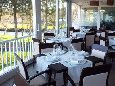 a restaurant with white tables and chairs and windows at Hotel Ansuiña in Baños de Molgas