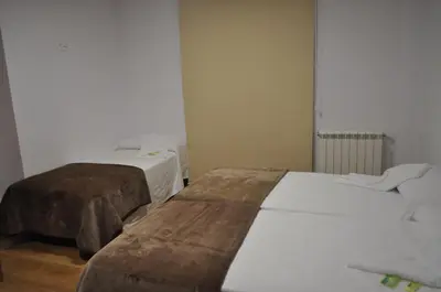 two beds in a room with white walls and wooden floors at Pons Minea in Portomarin
