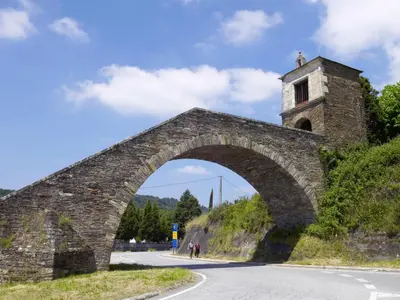an old stone bridge with a tower on a hill at Pons Minea in Portomarin