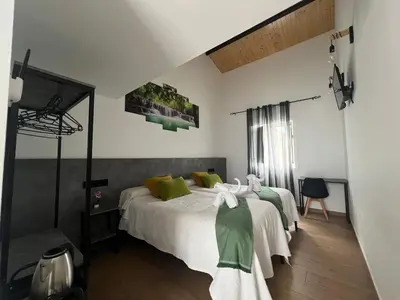 a bedroom with a bed with white sheets and green pillows at Pensión Mar in Portomarin