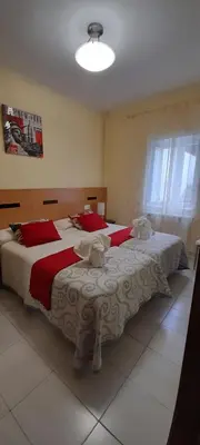 a bedroom with two beds with red and white sheets at Pensión Mar in Portomarin