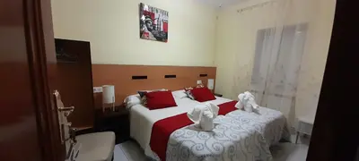 a bedroom with two beds with red and white sheets at Pensión Mar in Portomarin