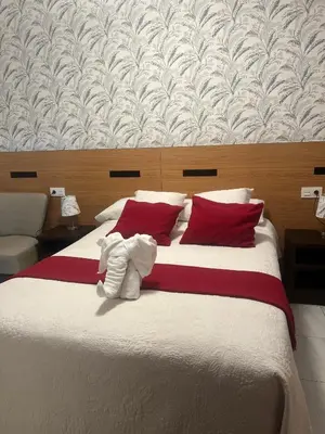 a bedroom with a large bed with red and white pillows at Pensión Mar in Portomarin