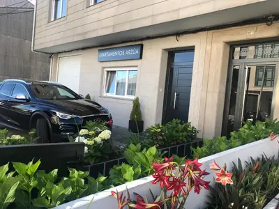 a car parked in front of a building with flowers at Viviendas Uso Turístico Arzúa in Arzúa