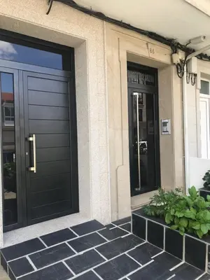 a house with a black garage door and some plants at Viviendas Uso Turístico Arzúa in Arzúa