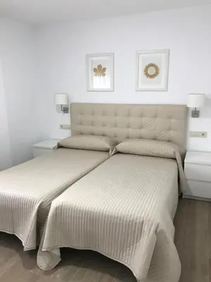 two beds in a bedroom with white walls at Viviendas Uso Turístico Arzúa in Arzúa