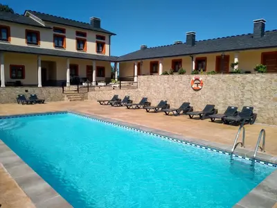 a swimming pool with chairs next to a building at Apartamentos Navalin in Tapia de Casariego