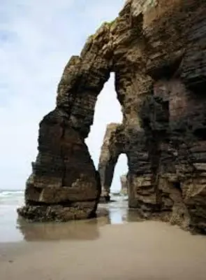 a rock formation on the beach next to the ocean at Apartamentos Navalin in Tapia de Casariego