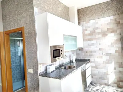 a white kitchen with a sink and a microwave at Apartamentos Navalin in Tapia de Casariego