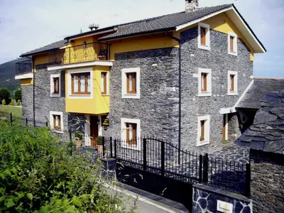 a stone house with a fence in front of it at Apartamentos Rurales Los Galpones in Coaña