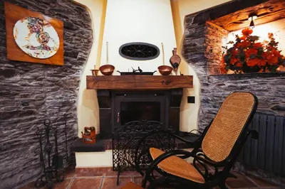 a living room with a stone fireplace and a chair at Apartamentos Rurales Los Galpones in Coaña