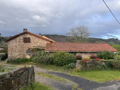 a stone house with a red tile roof at Casa Rural A Cobacha in Paderne