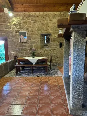 a dining room with a table and a stone wall at Casa Rural A Cobacha in Paderne