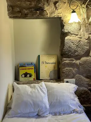 a bedroom with a bed in a stone wall at Casa Rural A Cobacha in Paderne