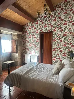 a bedroom with a large bed with floral wallpaper at Casa Rural A Cobacha in Paderne