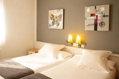 a bedroom with two white beds and two lamps at Hotel La Casa Del Abuelo in Tapia de Casariego