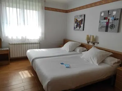 two beds in a hotel room with a window at Hotel La Casa Del Abuelo in Tapia de Casariego