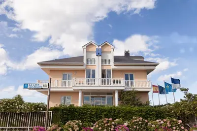 a large pink house with a balcony and flags at Hotel La Casa Del Abuelo in Tapia de Casariego