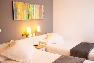 a hotel room with two beds and a painting on the wall at Hotel La Casa Del Abuelo in Tapia de Casariego