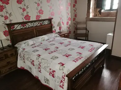 a bedroom with a bed with a red and white blanket at Casa de los Somoza in Melide