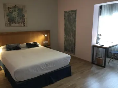 a bedroom with a bed and a table and a window at Hotel Celanova in Celanova
