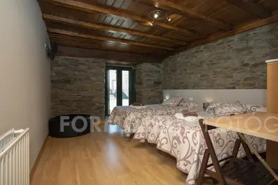 a bedroom with two beds and a stone wall at Pension Siete en el Camino in Sarria