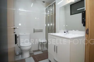 a white bathroom with a toilet and a sink at Pension Siete en el Camino in Sarria