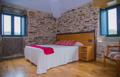 a bedroom with a bed and a brick wall at Pension Albergue Alborada in Salceda